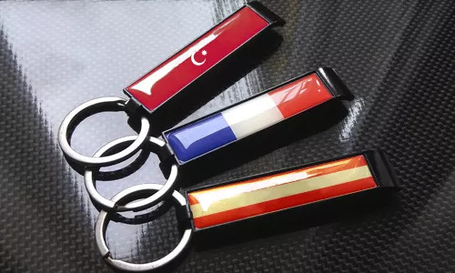 three bottle opener keychains with flags