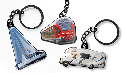 Keychains shaped like a sailboat, a red train, and a motorhome, shown as customizable travel-themed accessories