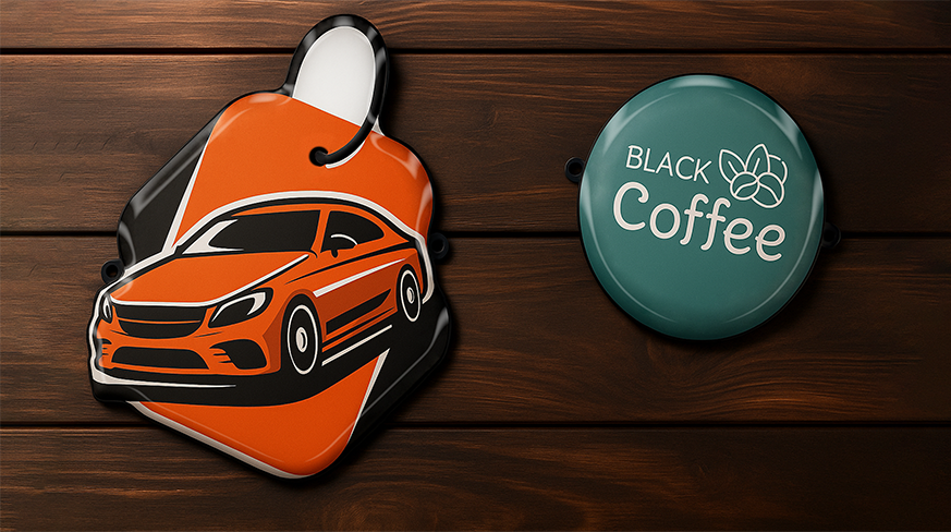 Due portachiavi – illustrazione di auto sportiva arancione su un esagono e insegna pubblicitaria in acrilico con logo BLACK Coffee su un cerchio turchese.