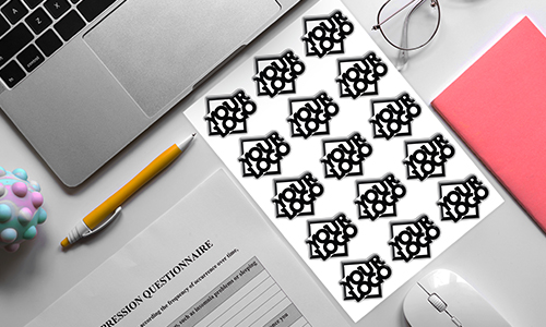 Postazione di lavoro con laptop, penna, quaderno e foglio di adesivi 